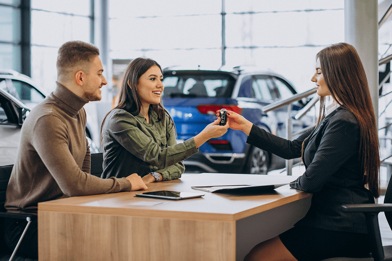 A woman is handing keys to two people.