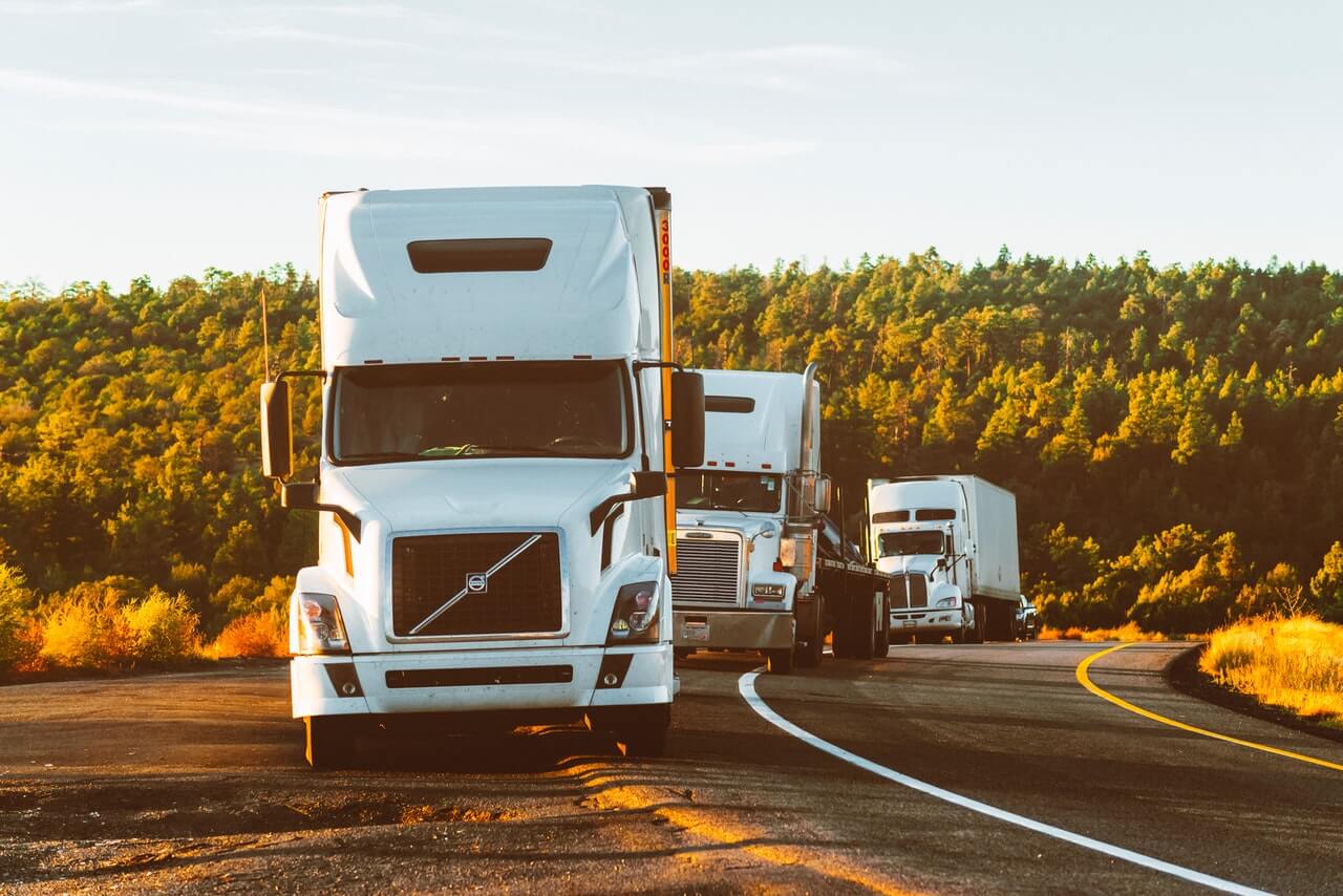 A group of trucks driving down the road.