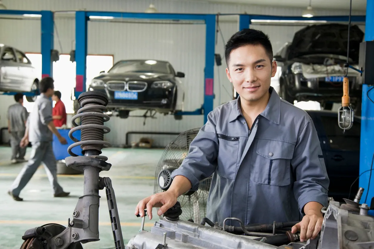 A man in blue shirt standing next to car parts.