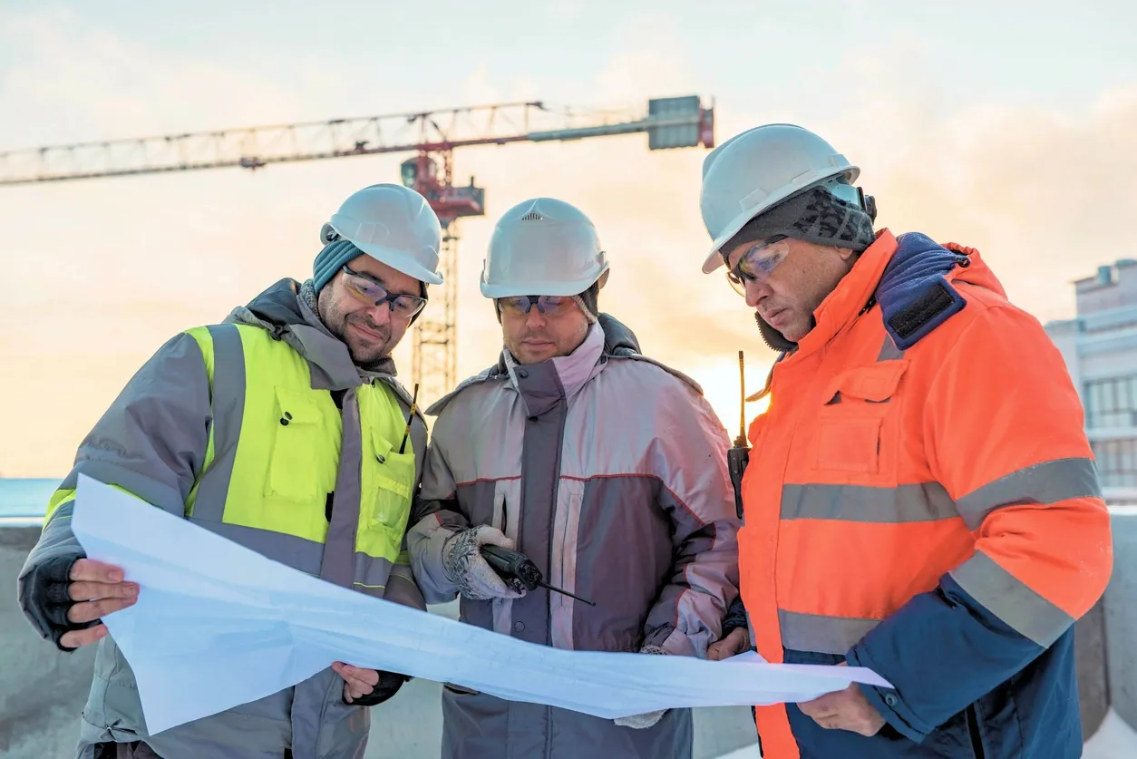 Three men in hard hats looking at a paper.