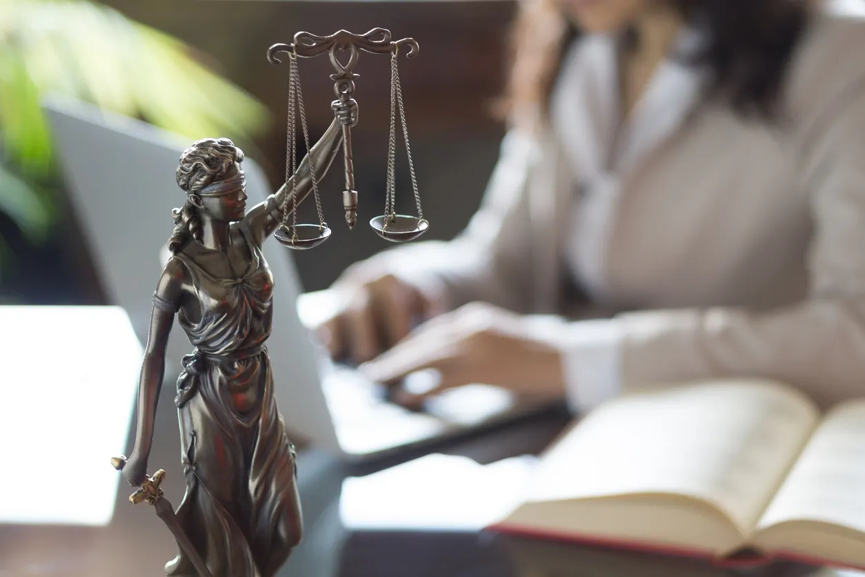 A statue of lady justice and a woman in the background.